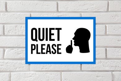 Quiet Please sign with shush gesture image on white brick wall