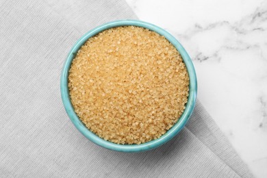 Photo of Brown sugar in bowl on white marble table, top view