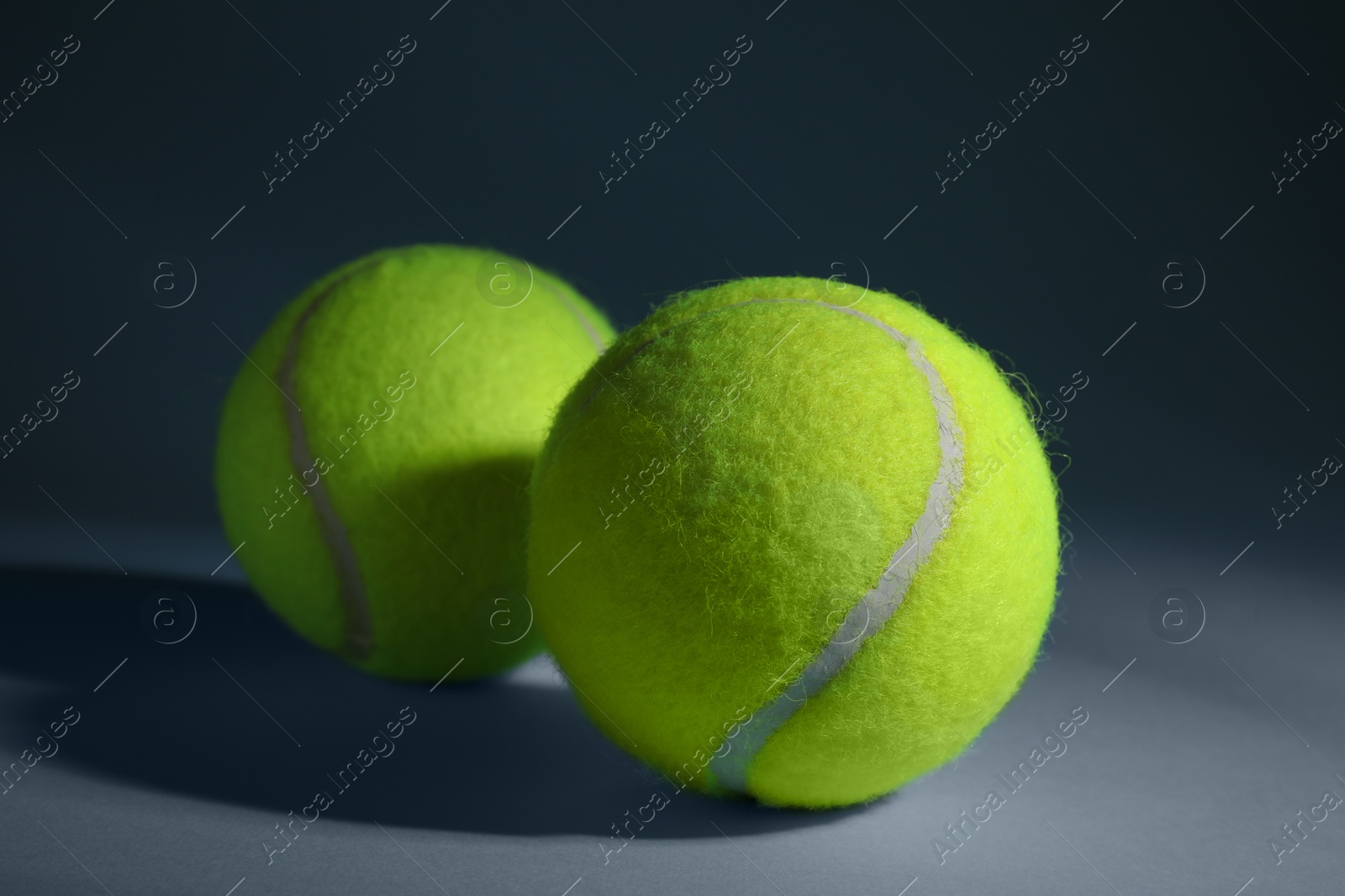 Photo of Two tennis balls on dusty light blue background, closeup