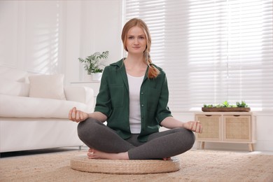 Photo of Woman meditating on wicker mat at home