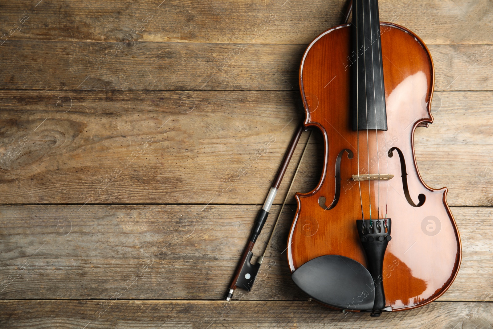 Photo of Beautiful violin and bow on wooden table, top view. Space for text