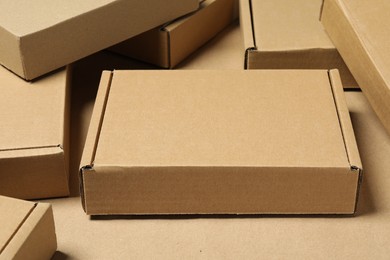 Many closed cardboard boxes on light brown background, closeup