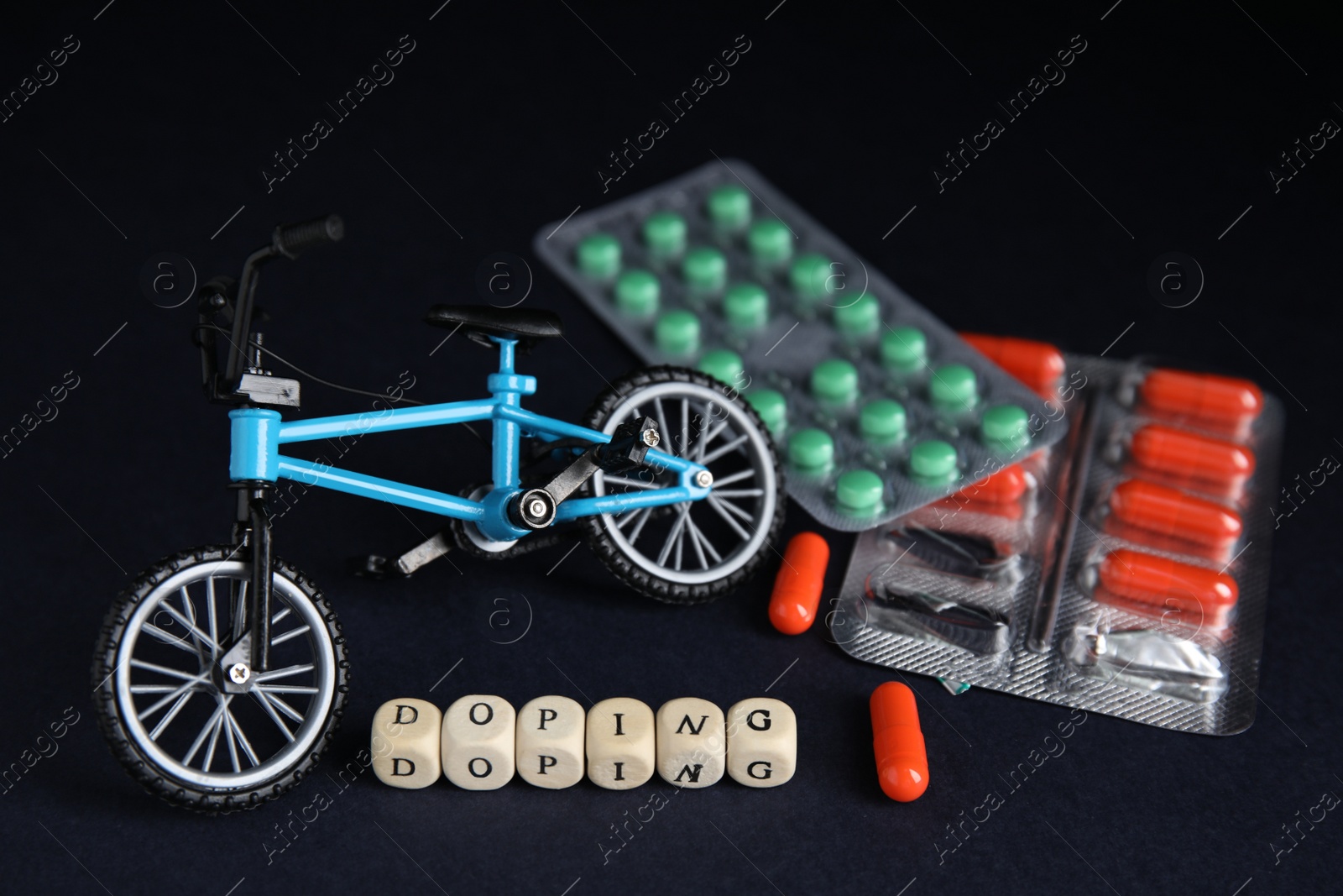 Photo of Word Doping, pills and bicycle model on black background