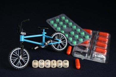 Photo of Word Doping, pills and bicycle model on black background