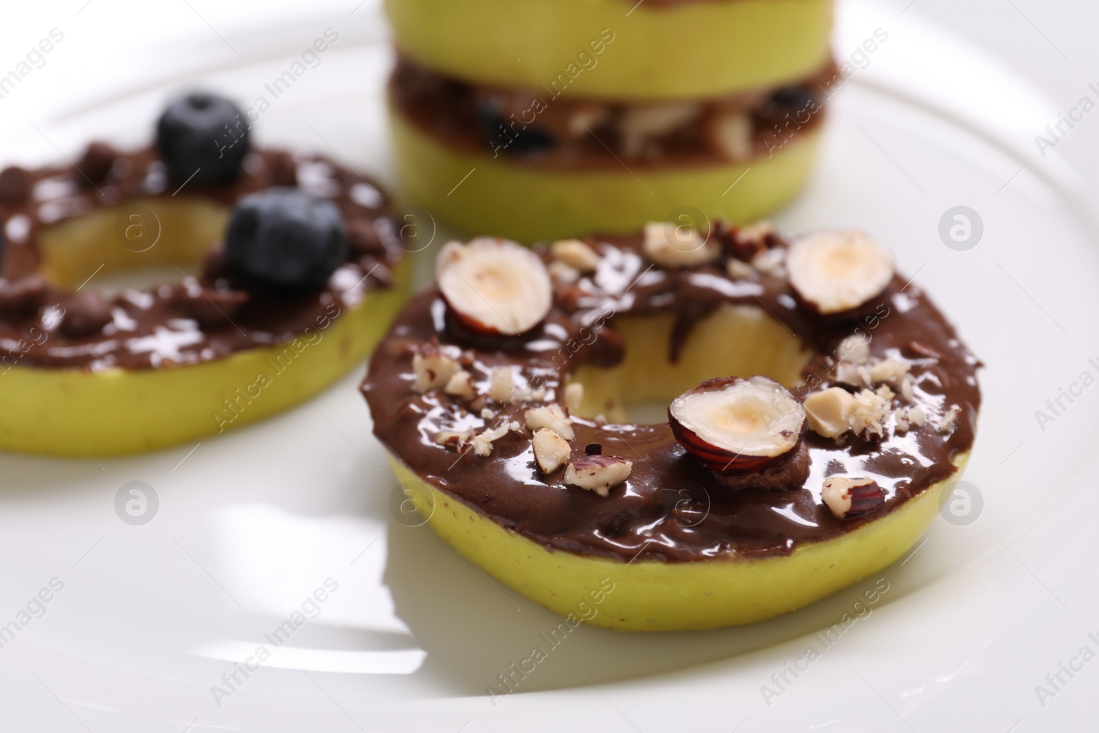 Photo of Fresh apples with nut butters, blueberries and hazelnuts on plate, closeup
