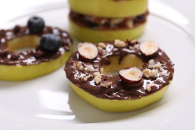 Photo of Fresh apples with nut butters, blueberries and hazelnuts on plate, closeup