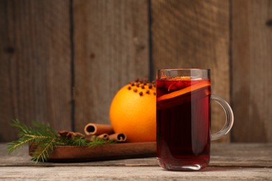 Aromatic mulled wine in glass cup on wooden table, space for text