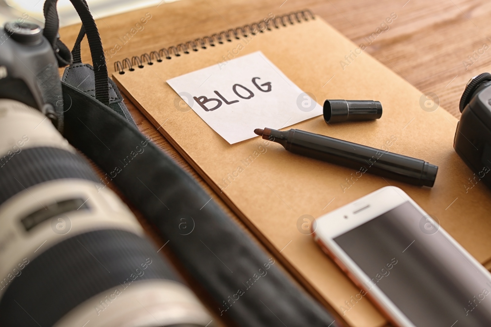 Photo of Blogger notes with various equipment on wooden table, closeup