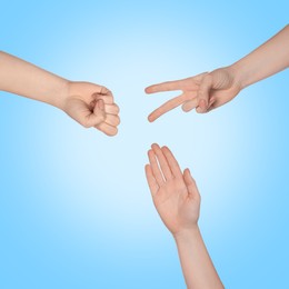 People playing rock, paper and scissors on light blue background, top view