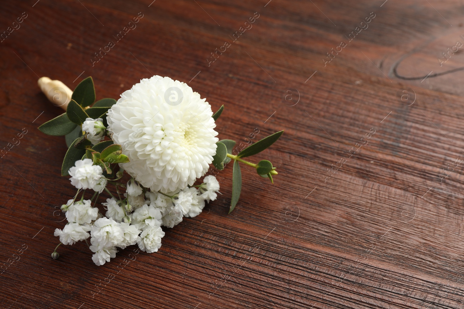 Photo of Small stylish boutonniere on wooden table, space for text
