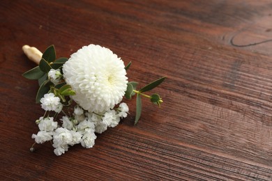 Small stylish boutonniere on wooden table, space for text