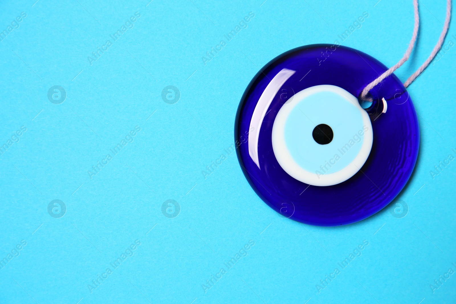 Photo of Evil eye amulet on light blue background, top view. Space for text