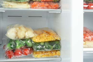 Plastic bags with different frozen vegetables in refrigerator