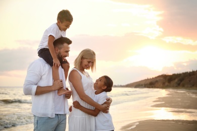 Happy family on sandy beach near sea at sunset