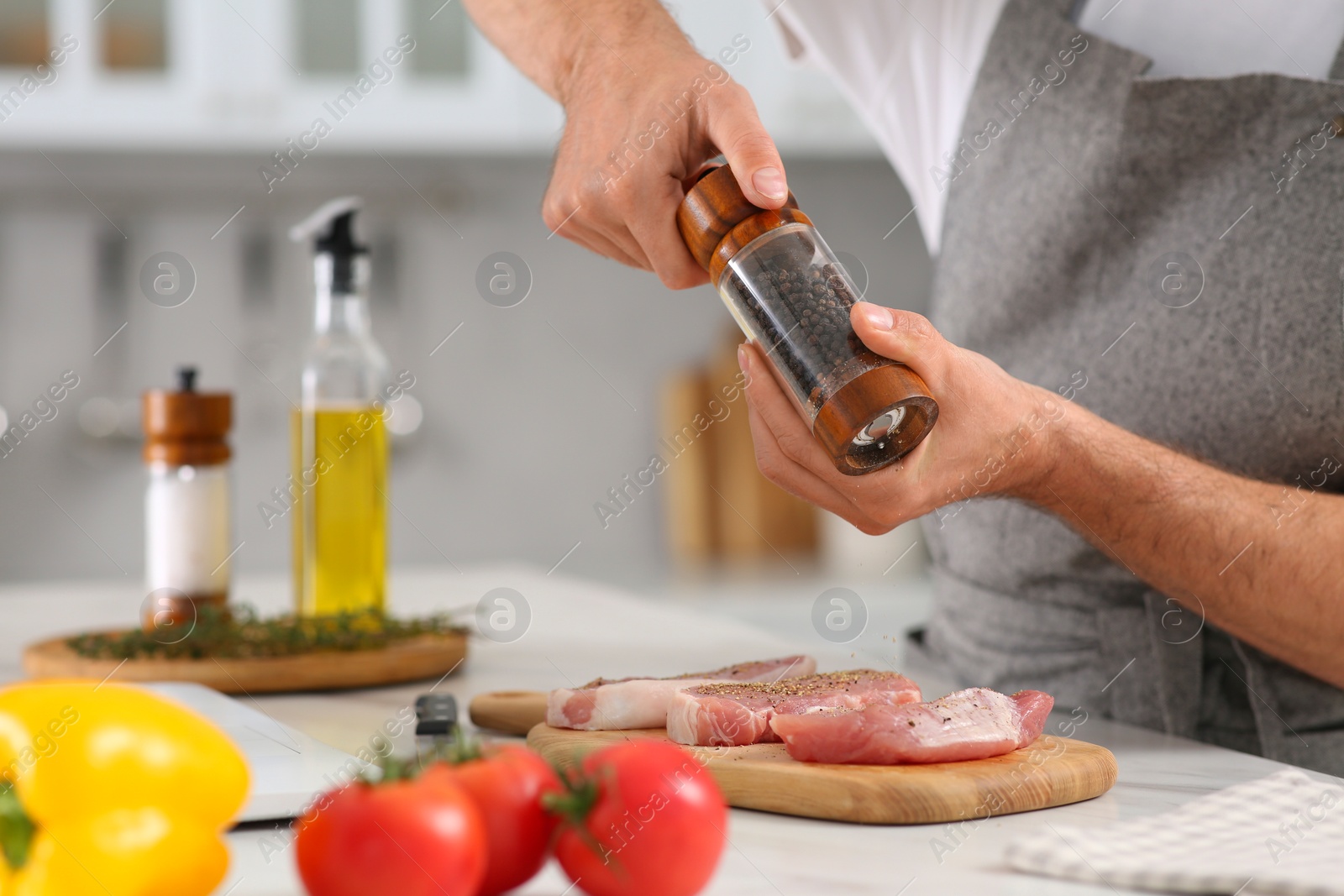 Photo of Man peppering steak at table in kitchen, closeup. Online cooking course