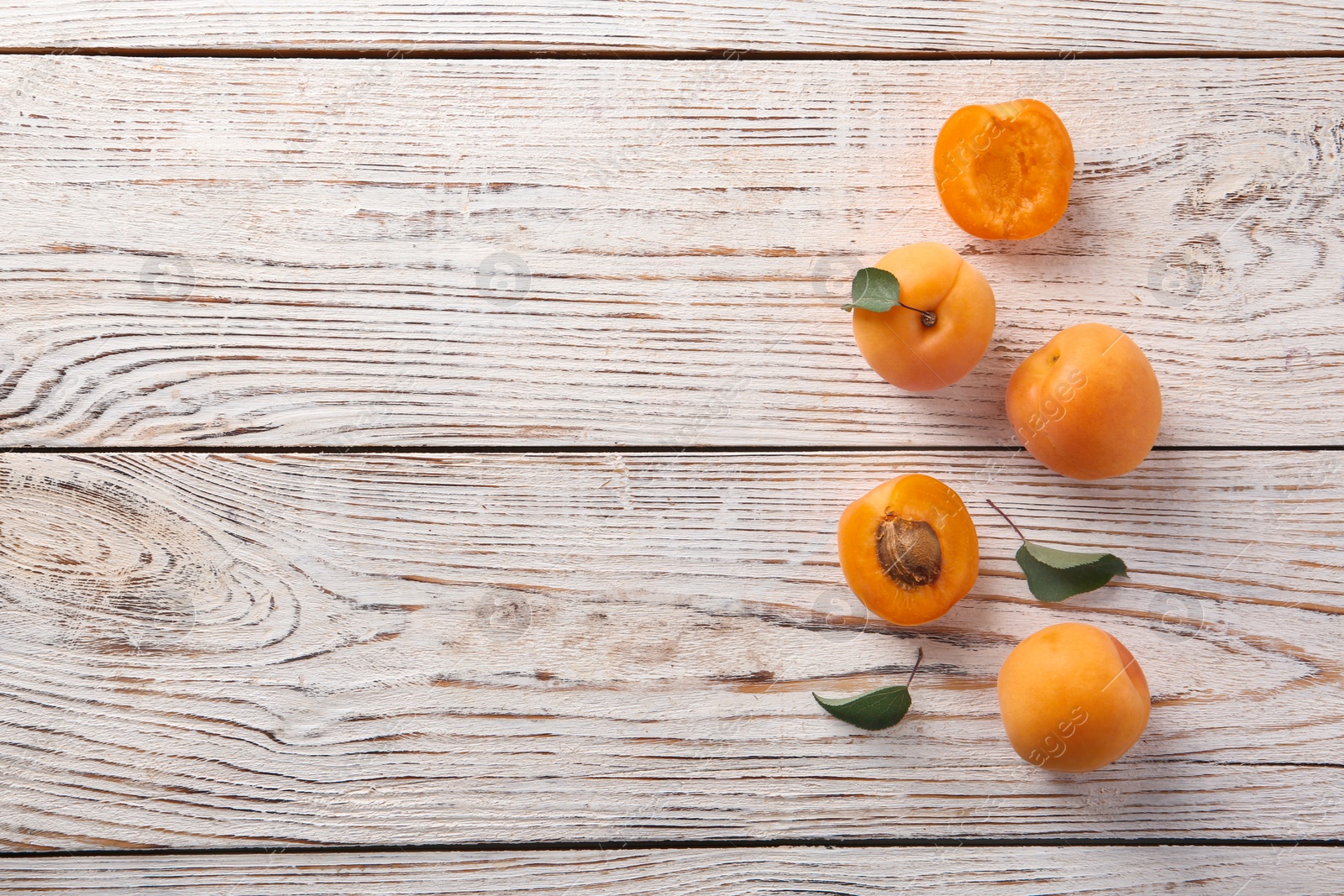 Photo of Delicious ripe apricots on white wooden background, flat lay. Space for text