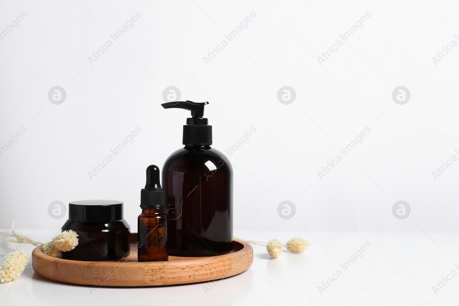 Photo of Different cosmetic products and dry spikes on white wooden table. Space for text