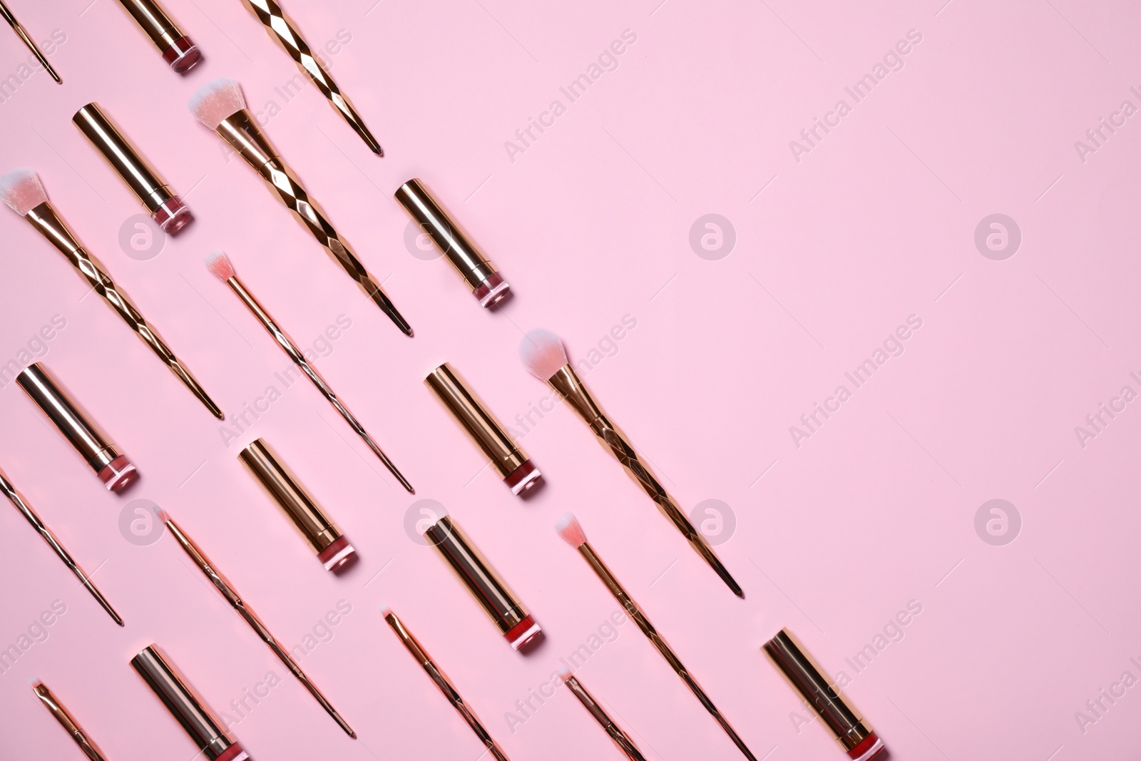 Photo of Makeup brushes and lipsticks on pink background, flat lay. Space for text