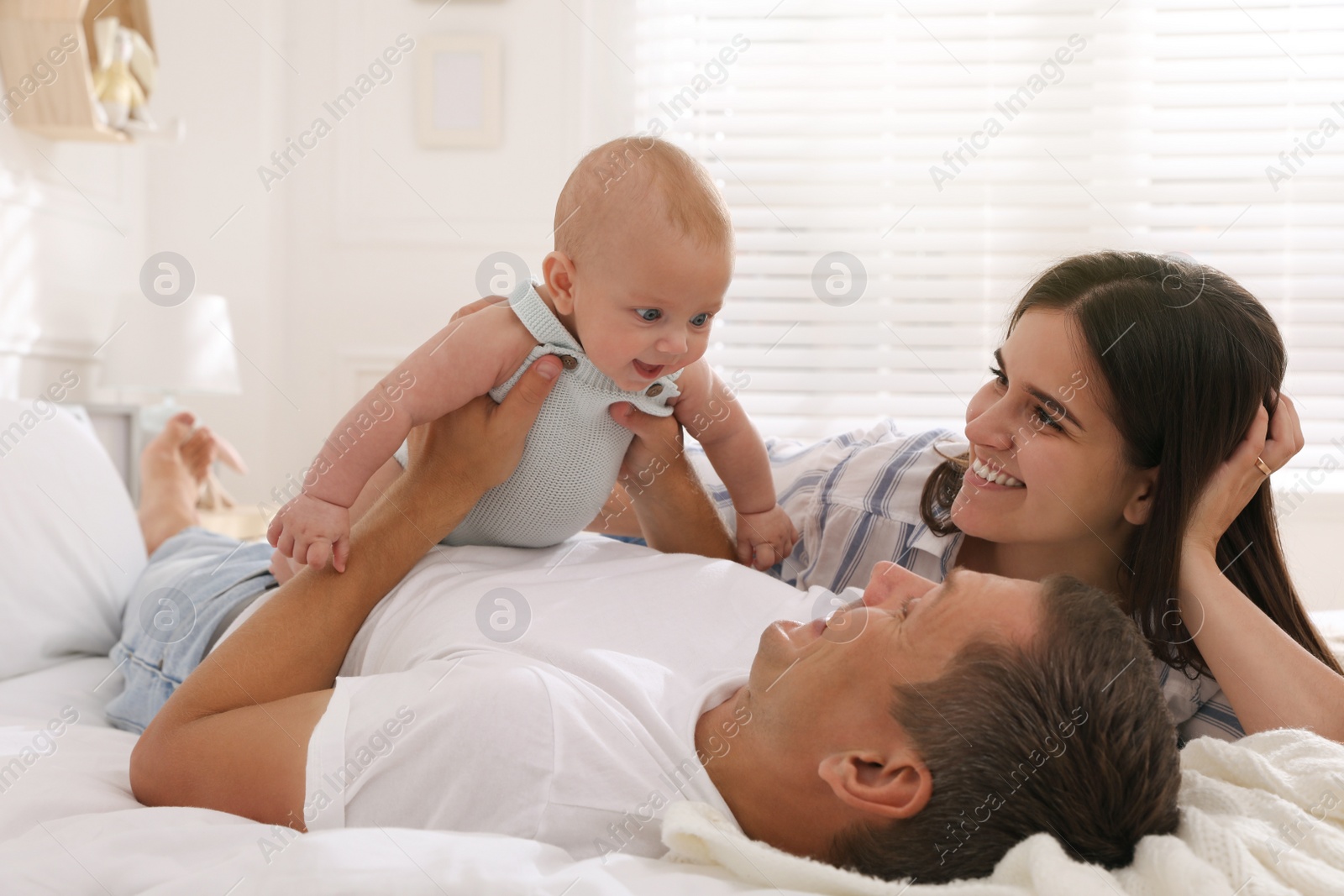 Photo of Happy family with their cute baby on bed at home