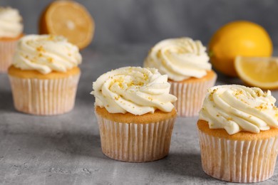 Delicious cupcakes with white cream and lemon zest on gray table, closeup
