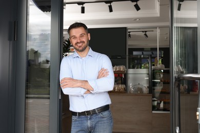 Photo of Happy business owner at door of his cafe. Space for text