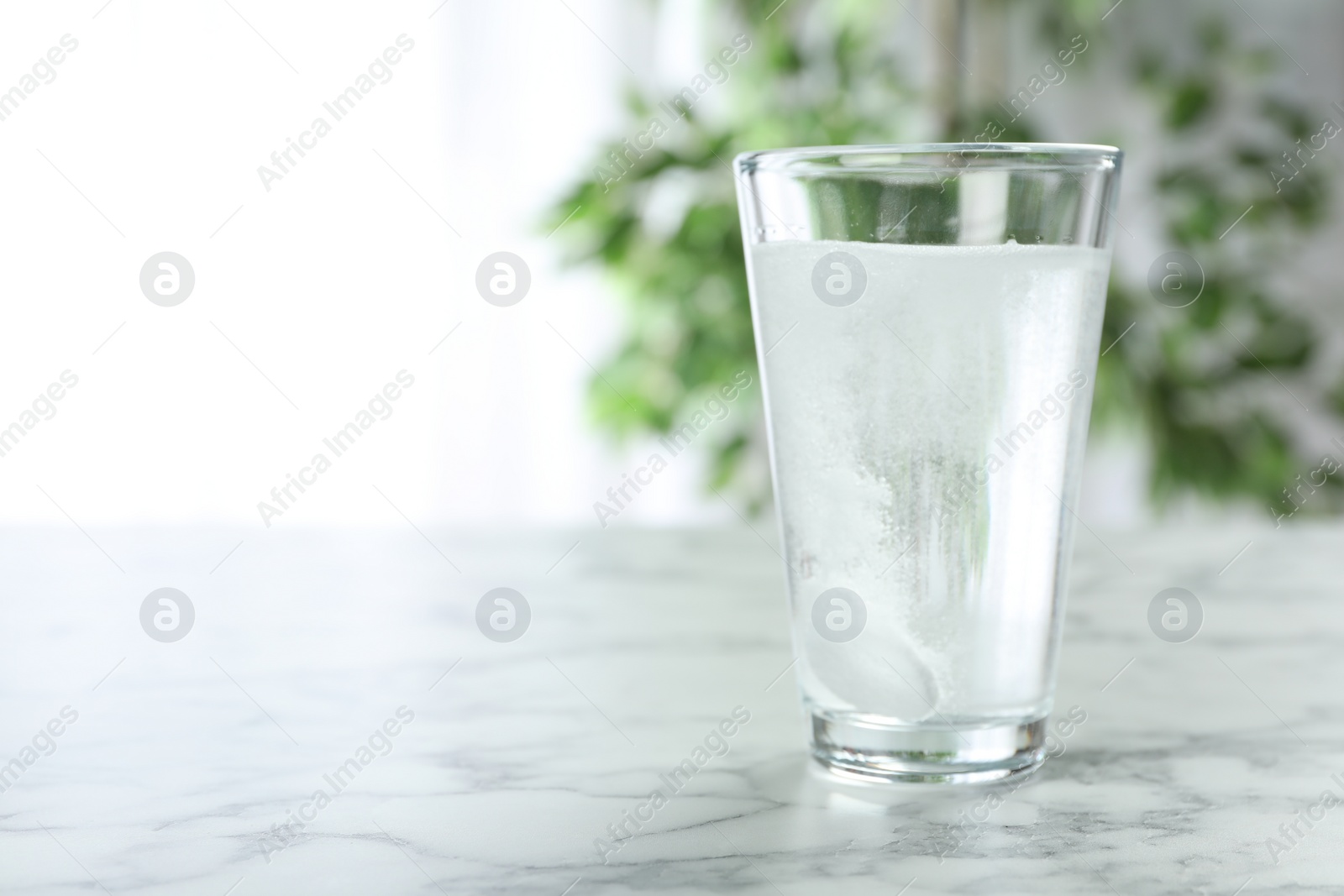 Photo of Glass of water with effervescent tablet on marble table indoors, space for text