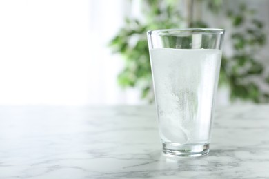 Photo of Glass of water with effervescent tablet on marble table indoors, space for text