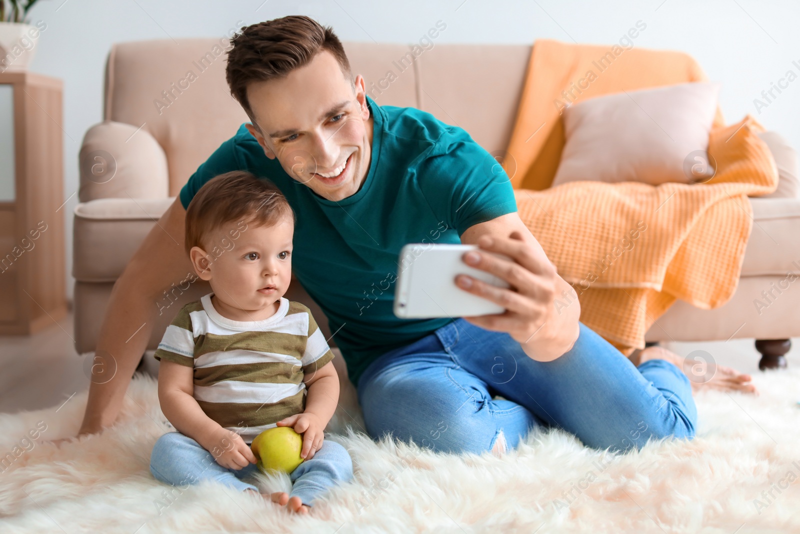 Photo of Young father with his cute little son taking selfie at home