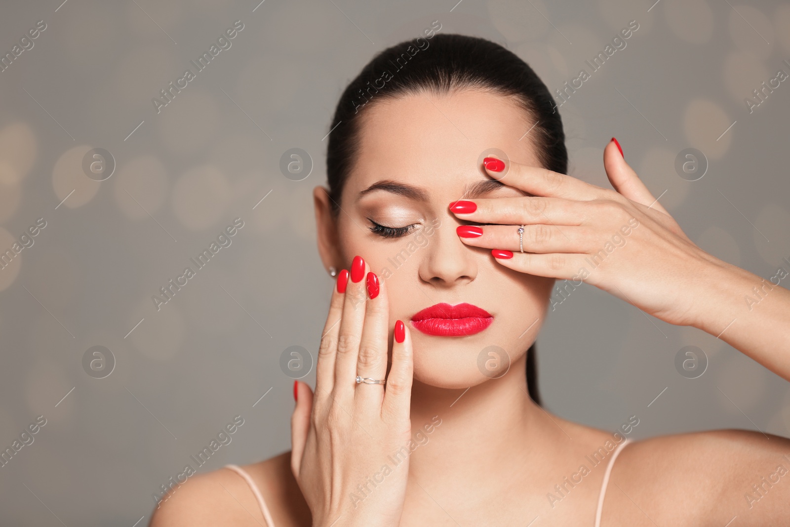 Photo of Portrait of beautiful young woman with bright manicure on blurred background. Nail polish trends