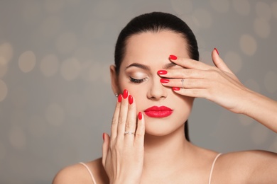 Portrait of beautiful young woman with bright manicure on blurred background. Nail polish trends