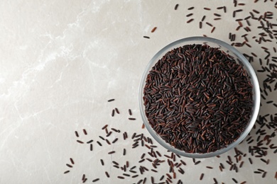 Bowl with brown rice on table, top view. Space for text