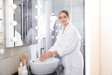 Young woman washing hands in bathroom. Using soap