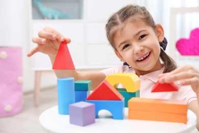 Photo of Cute child playing with colorful blocks at home