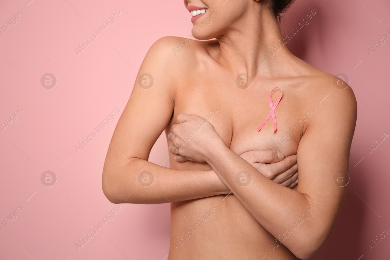 Photo of Naked woman with silk ribbon on color background, closeup. Breast cancer awareness concept