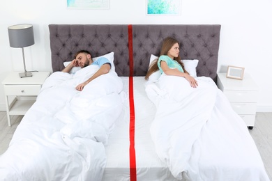 Photo of Upset couple with relationship problems lying separately in bed at home