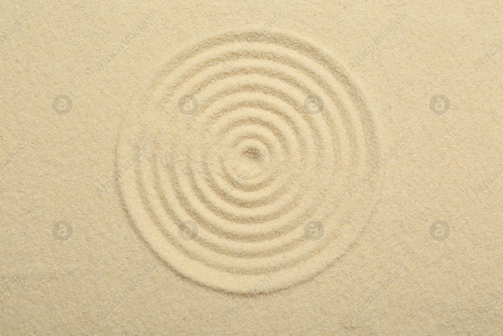 Photo of Zen rock garden. Circle pattern on beige sand, top view