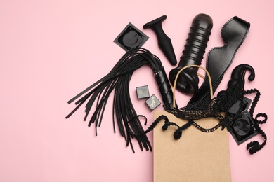 Shopping bag and different sex toys on pink background, flat lay. Space for text