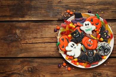 Tasty cookies and sweets for Halloween party on wooden table, top view. Space for text