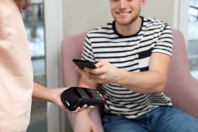 Client using smartphone and credit card machine for non cash payment in cafe