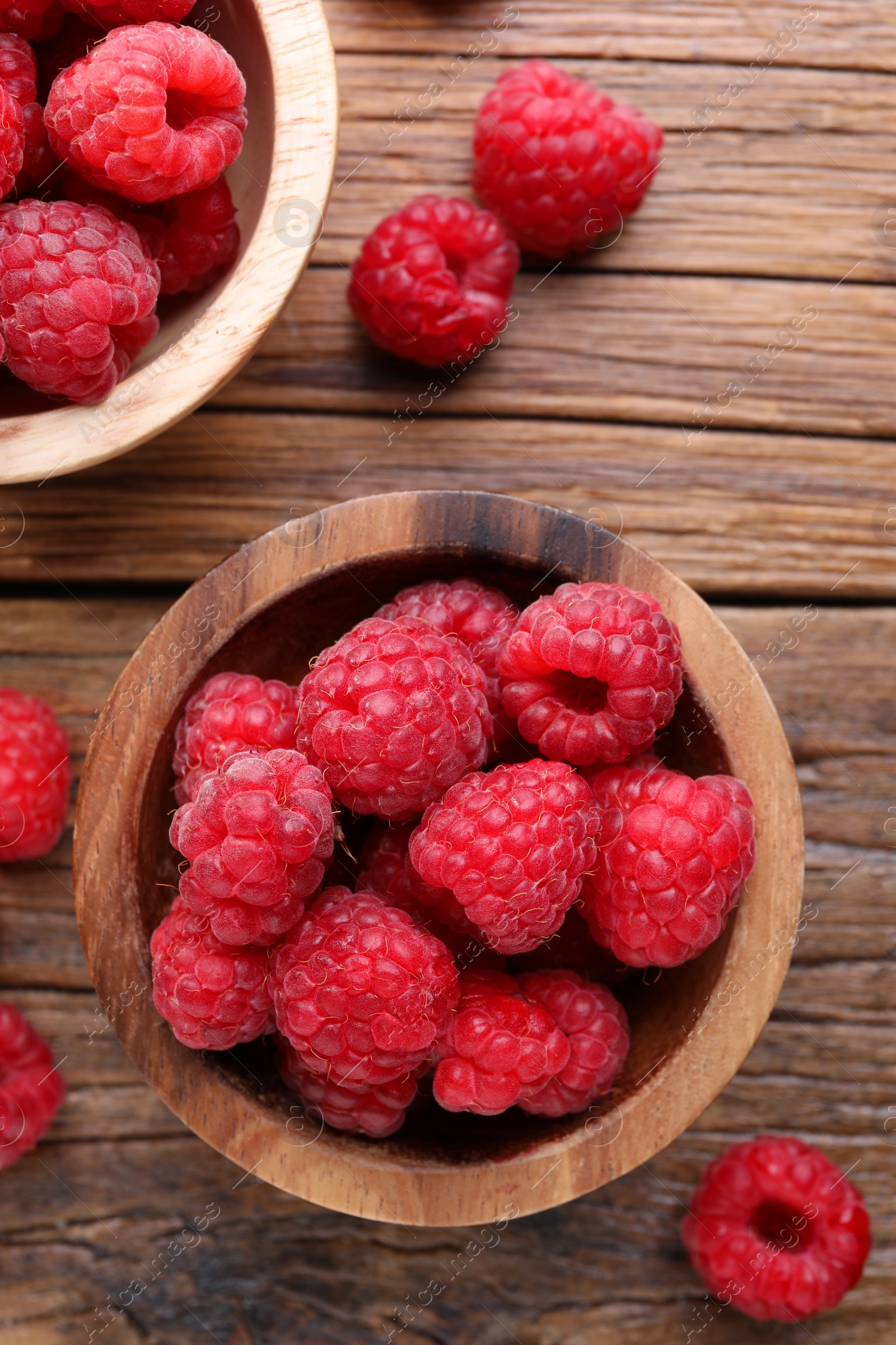 Photo of Tasty ripe raspberries on wooden table, flat lay