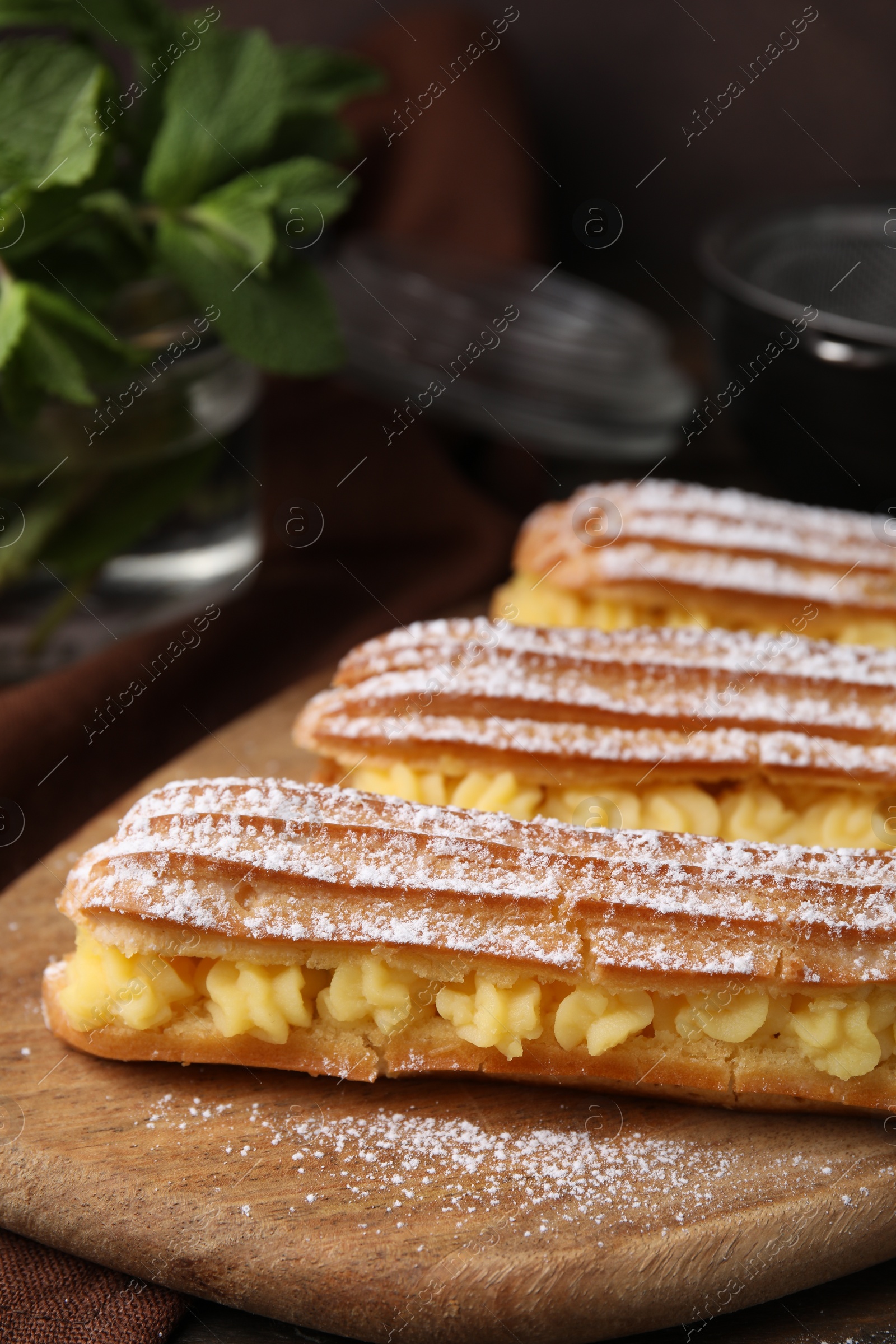 Photo of Delicious eclairs filled with cream on table