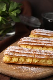 Delicious eclairs filled with cream on table