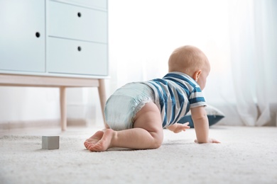 Photo of Cute little baby crawling on carpet indoors