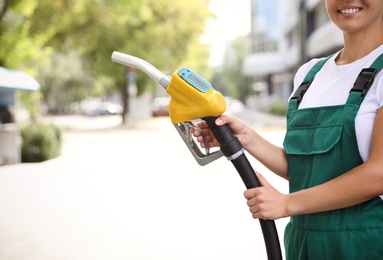 Photo of Young worker with fuel pump nozzle at modern gas station, closeup