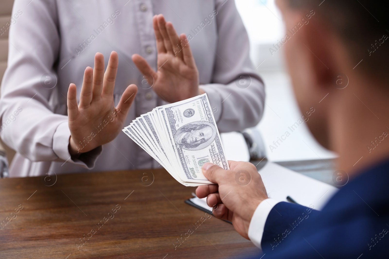 Photo of Woman refuses to take bribe money at wooden table, closeup