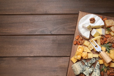 Photo of Cheese plate with rosemary and nuts on wooden table, top view. Space for text