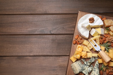 Cheese plate with rosemary and nuts on wooden table, top view. Space for text