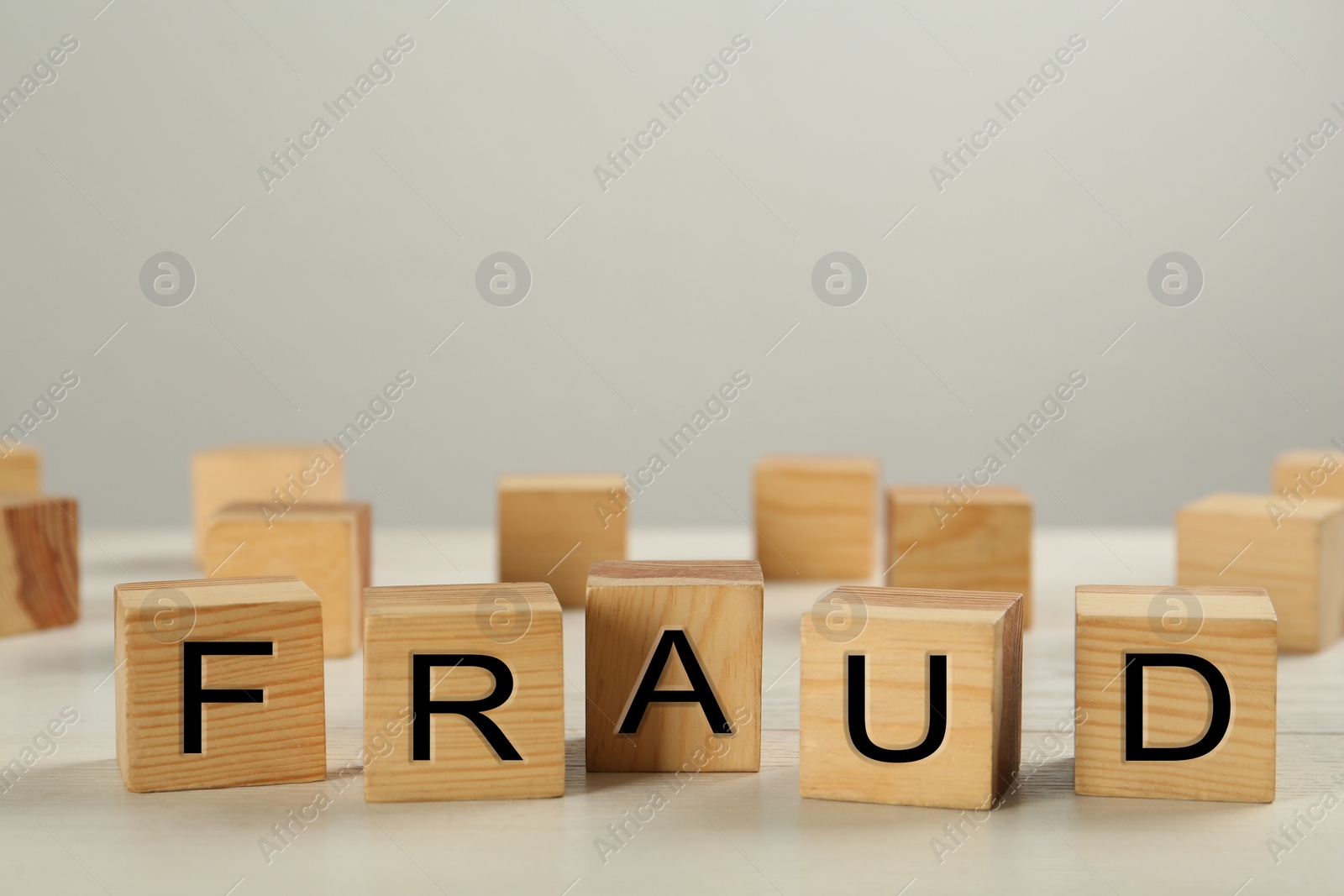 Photo of Wooden cubes with word Fraud on white table, space for text
