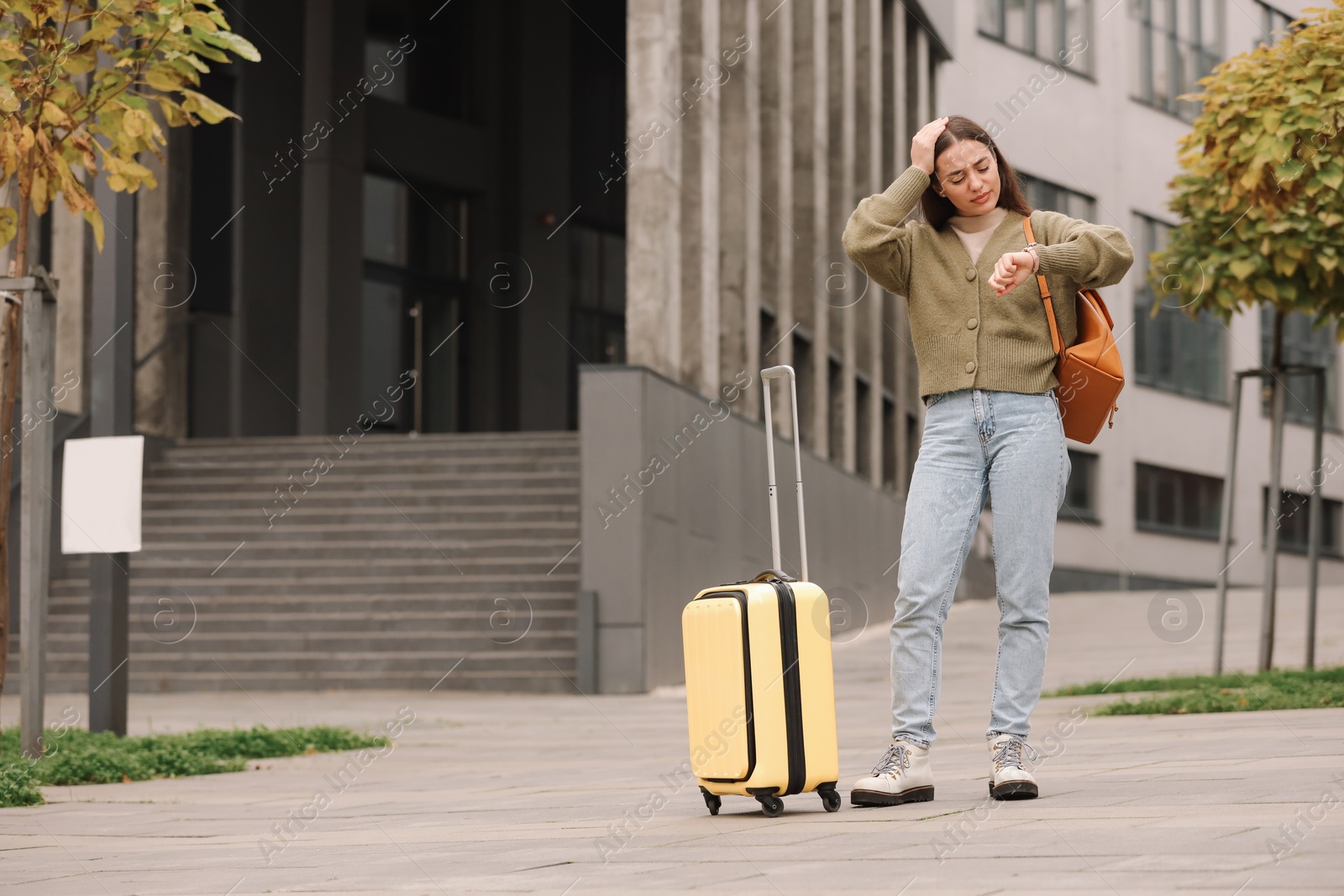 Photo of Being late. Worried woman with suitcase and backpack looking at watch outdoors, space for text