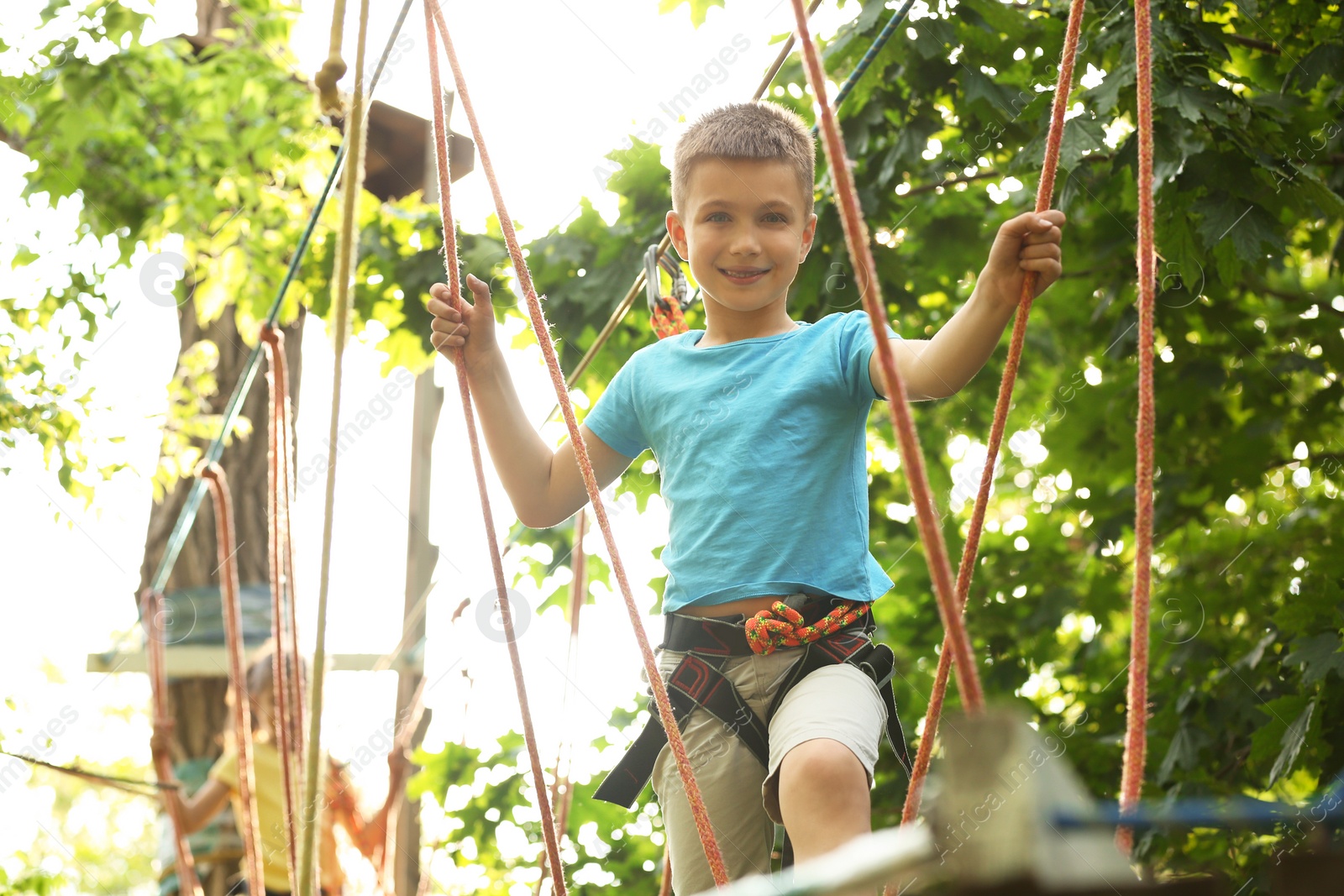 Photo of Little boy climbing in adventure park. Summer camp